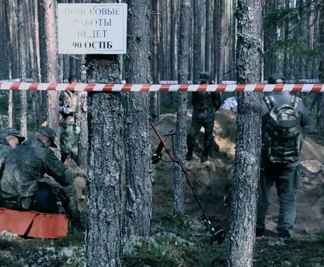 skupina ruských vojáků ohledává masový hrob v lese