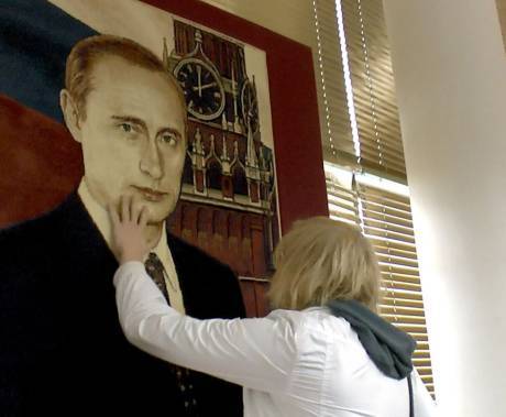 žena se rukou dotýká obrazu Vladimíra Putina na zdi