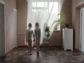dvě dívky schované za záclonou se drží za ruce