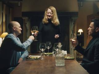 tři lidé si u stolu připíjejí vínem