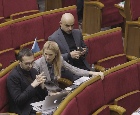 tři lidé sedí na sedačkách v sále
