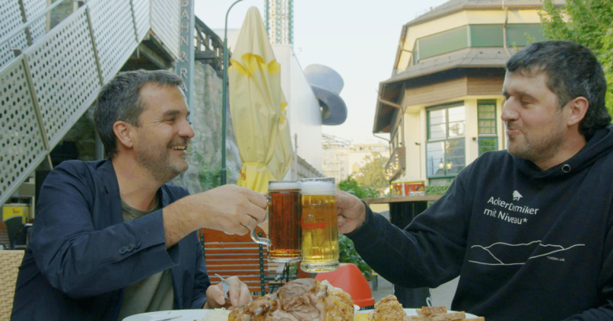 dva muži si připíjí pivem u stolu